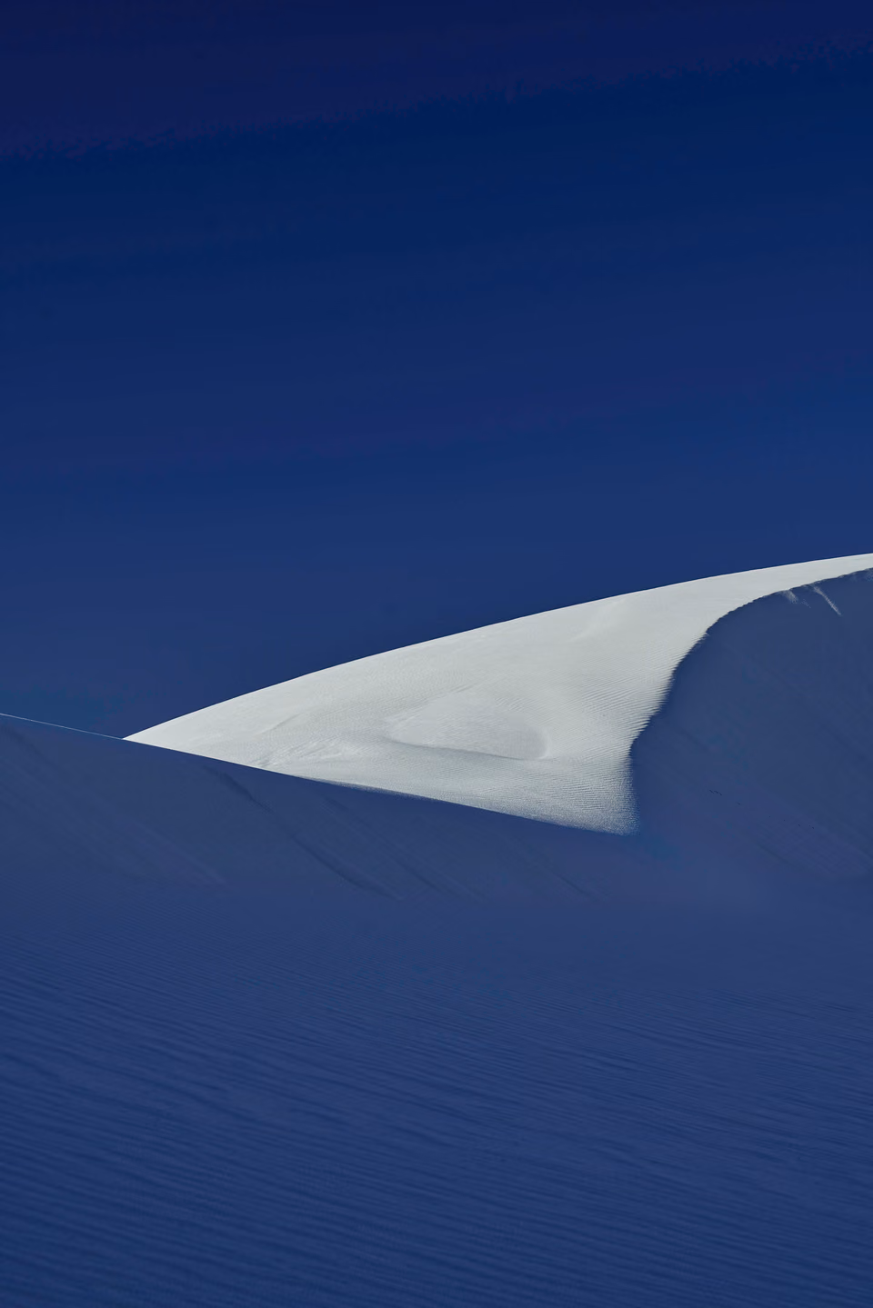 a lone person standing on top of a large sand dune

