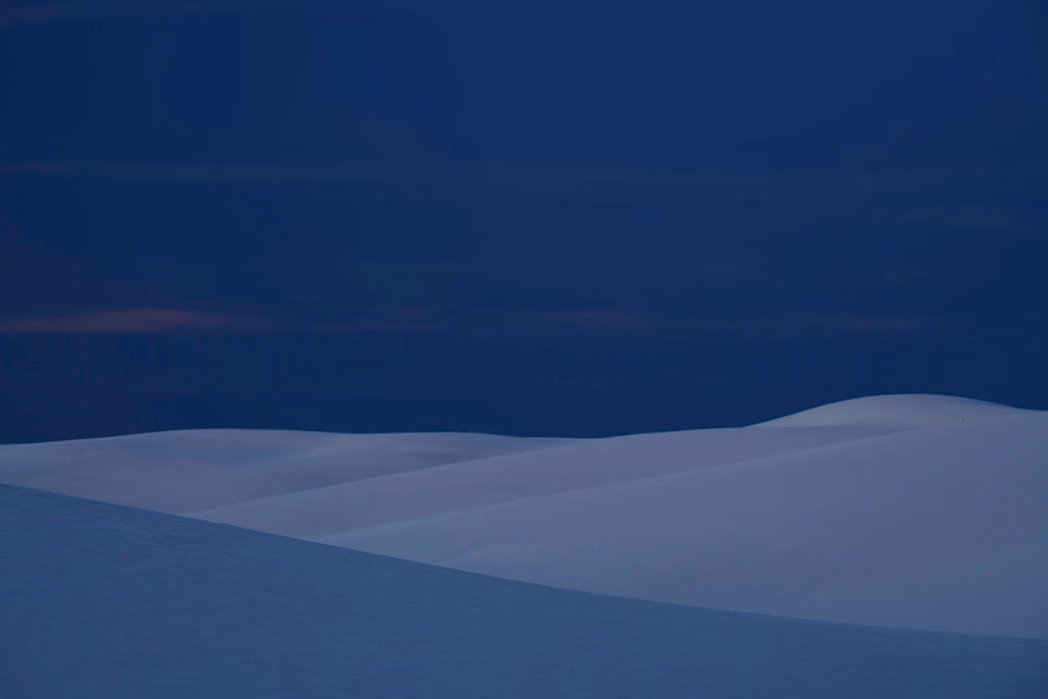 a lone person standing on top of a hill in the dark
