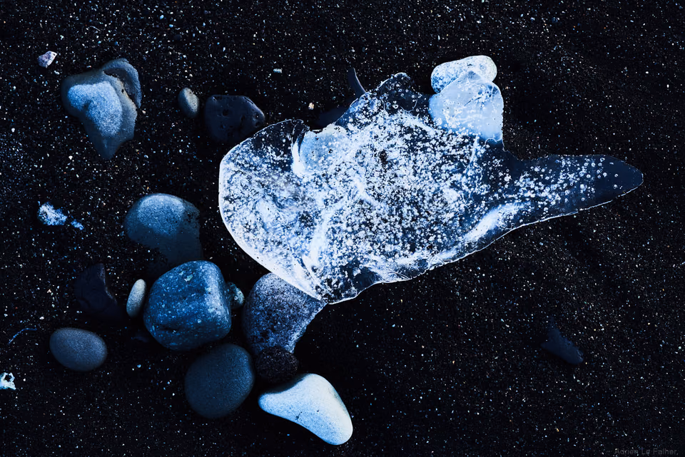 a piece of glass on the beach with some rocks
