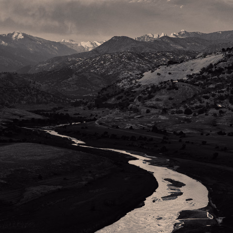 a black and white photo of a river in the mountains
