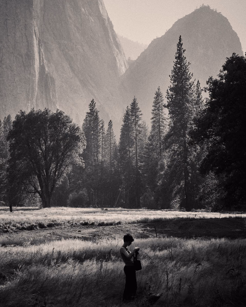 a person standing in the middle of a field with mountains in the background
