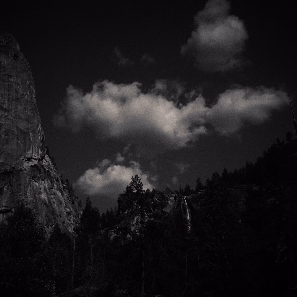 black and white photo of a mountain with clouds
