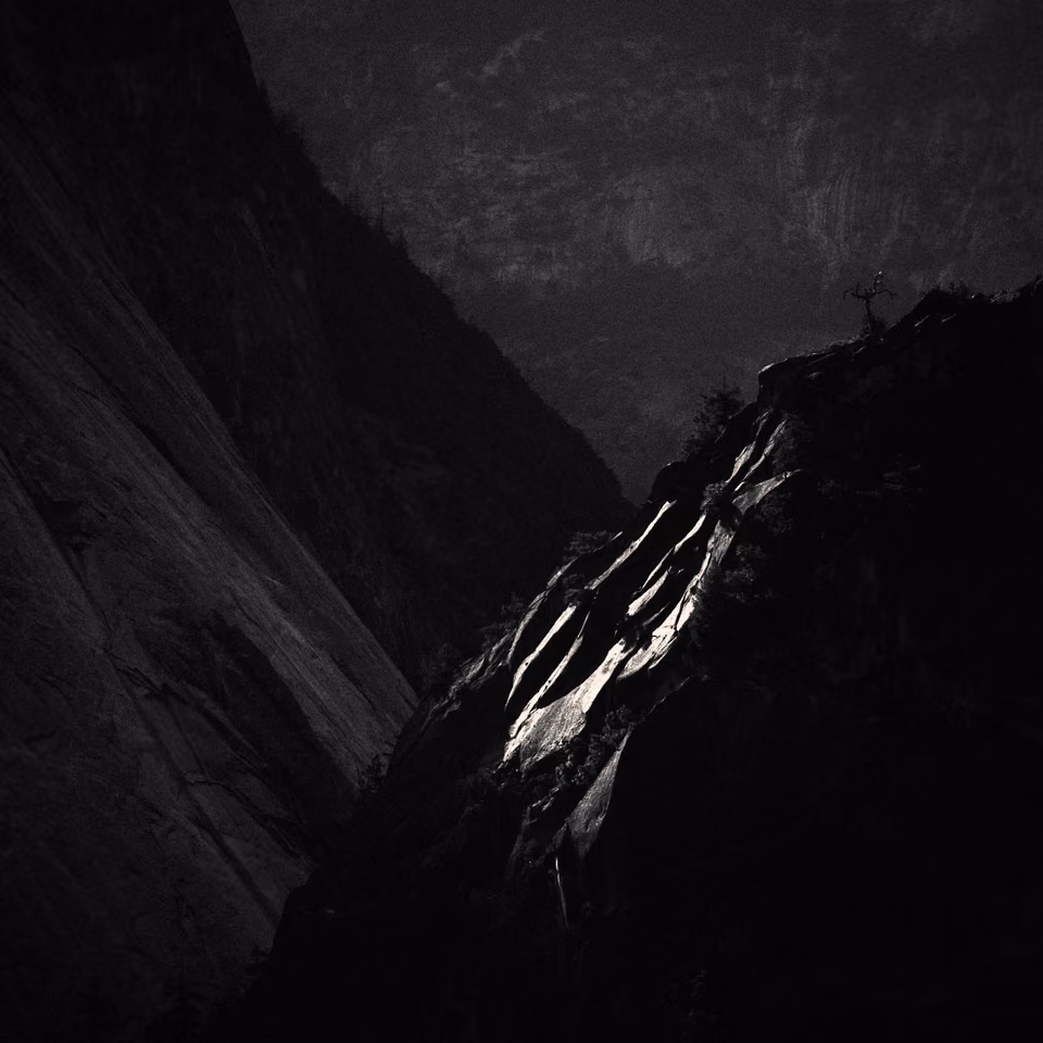 a black and white photo of a mountain with a rock
