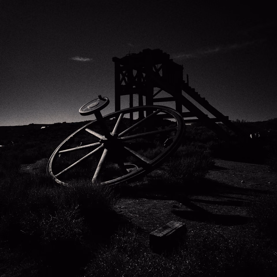 a black and white photo of a wheel in the desert
