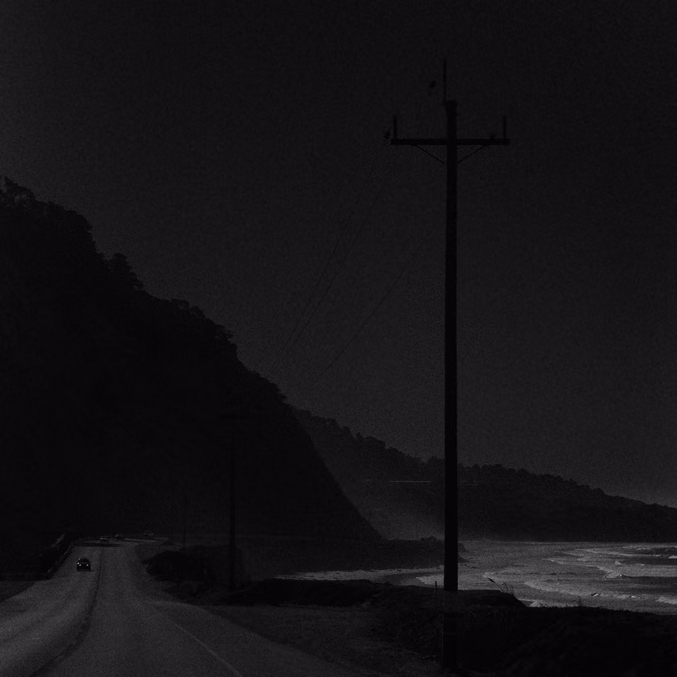a black and white photo of a road near the ocean
