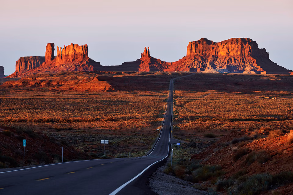 a long road with a highway sign in the distance
