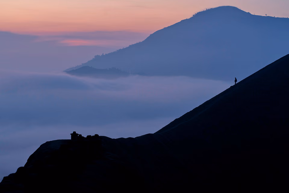 a person is standing on top of a mountain with fog in the background
