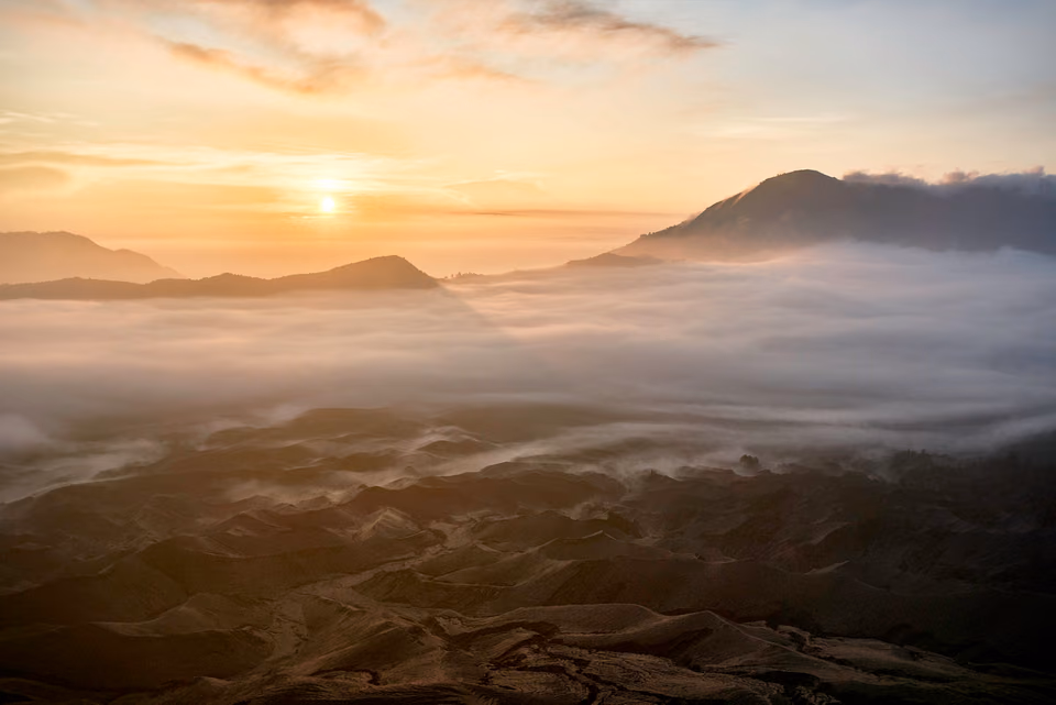 a sunrise over a valley with fog and mountains
