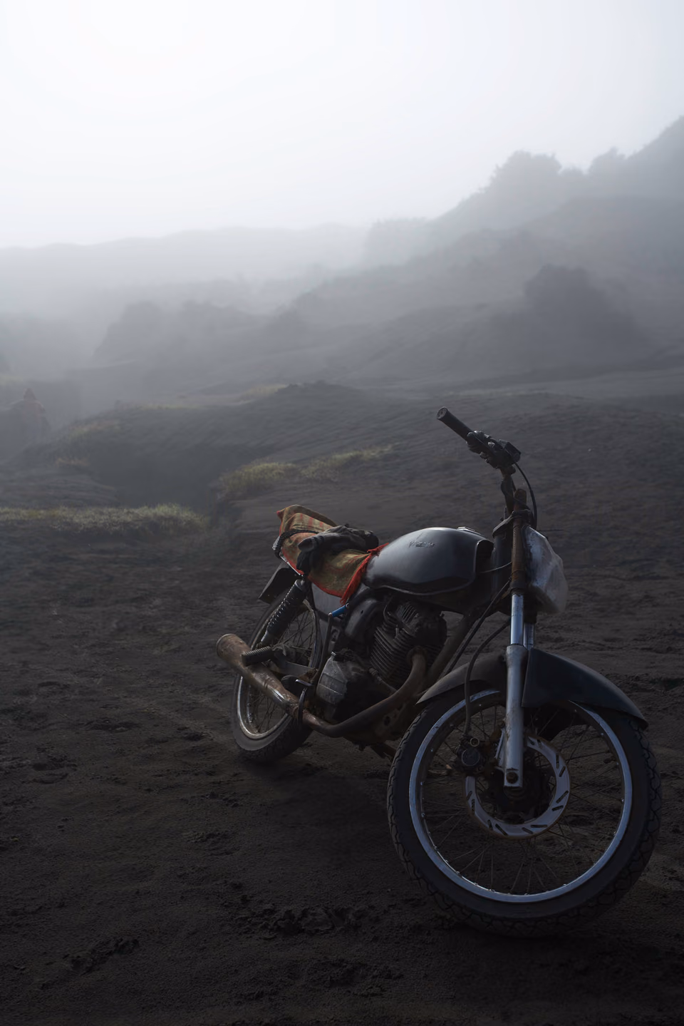 a motorcycle is parked on a foggy hill
