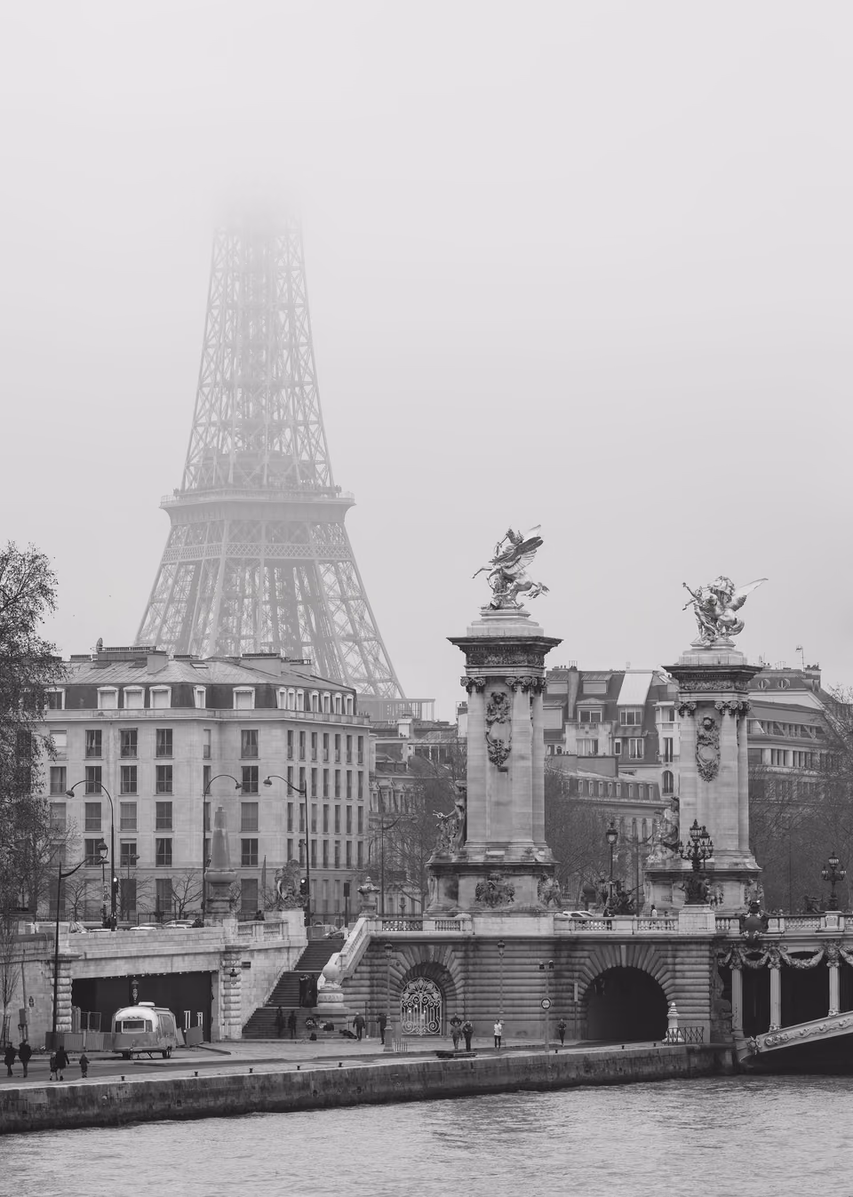 a black and white photo of the eiffel tower in the fog
