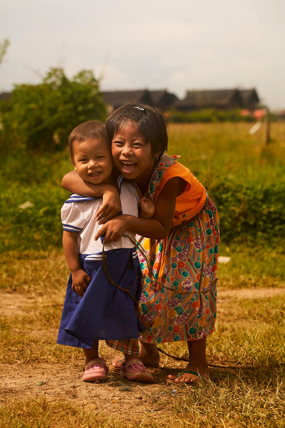 two little girls hugging each other in a field
