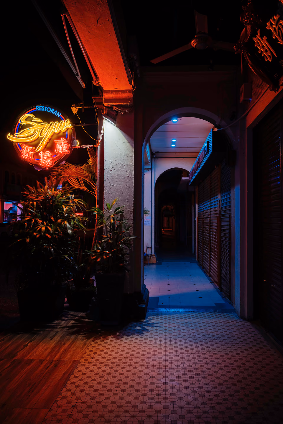 a street with a building on it and a neon sign
