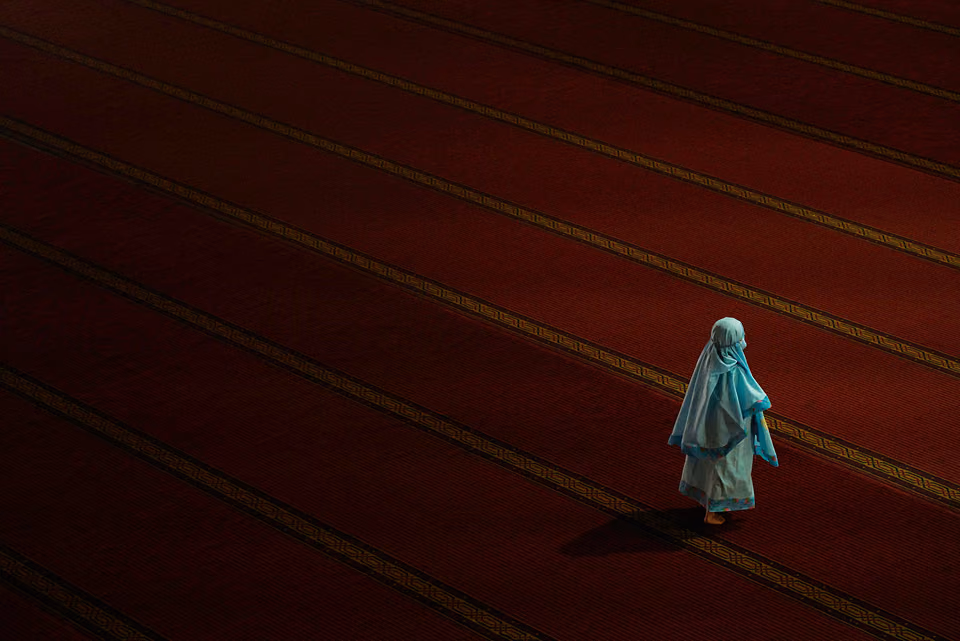 a woman in a white robe walking on a red carpet
