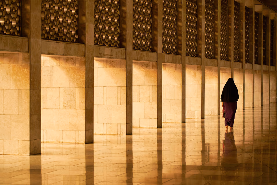 a woman walking down a hallway with a umbrella
