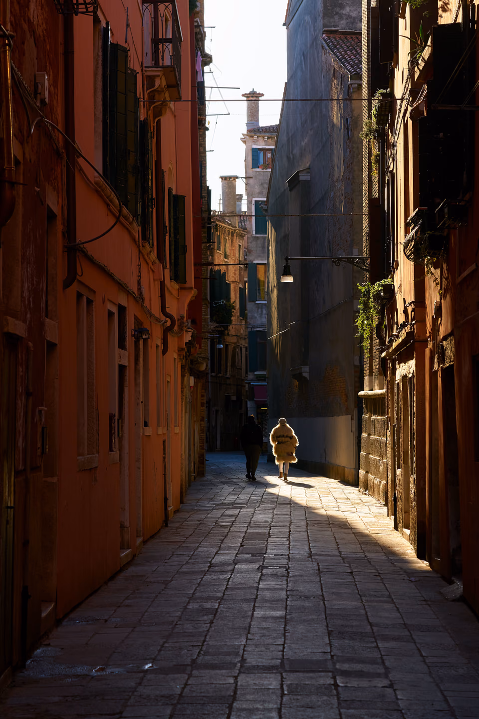 a person walking down a narrow alleyway in venice
