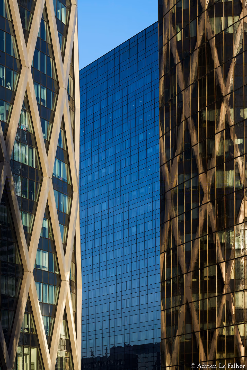 two tall buildings with glass windows and a blue sky
