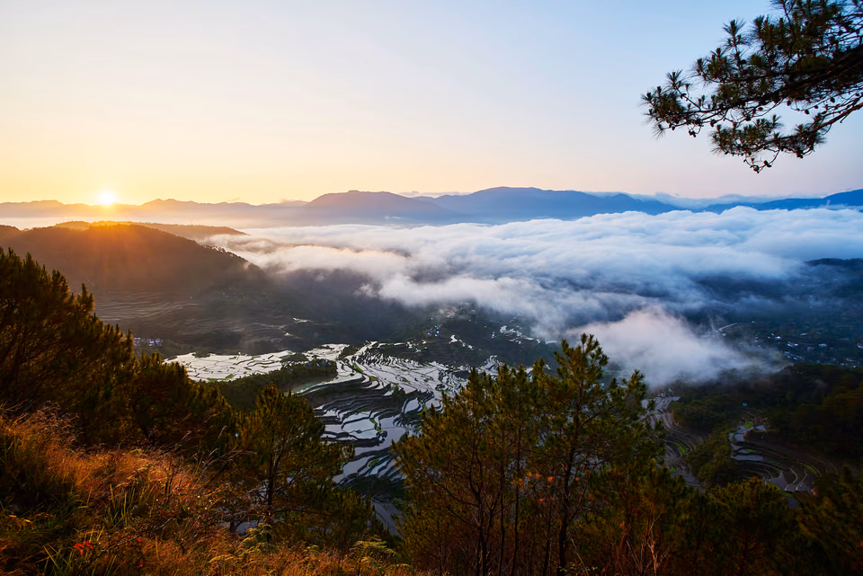 a view of the clouds and mountains from a hilltop
