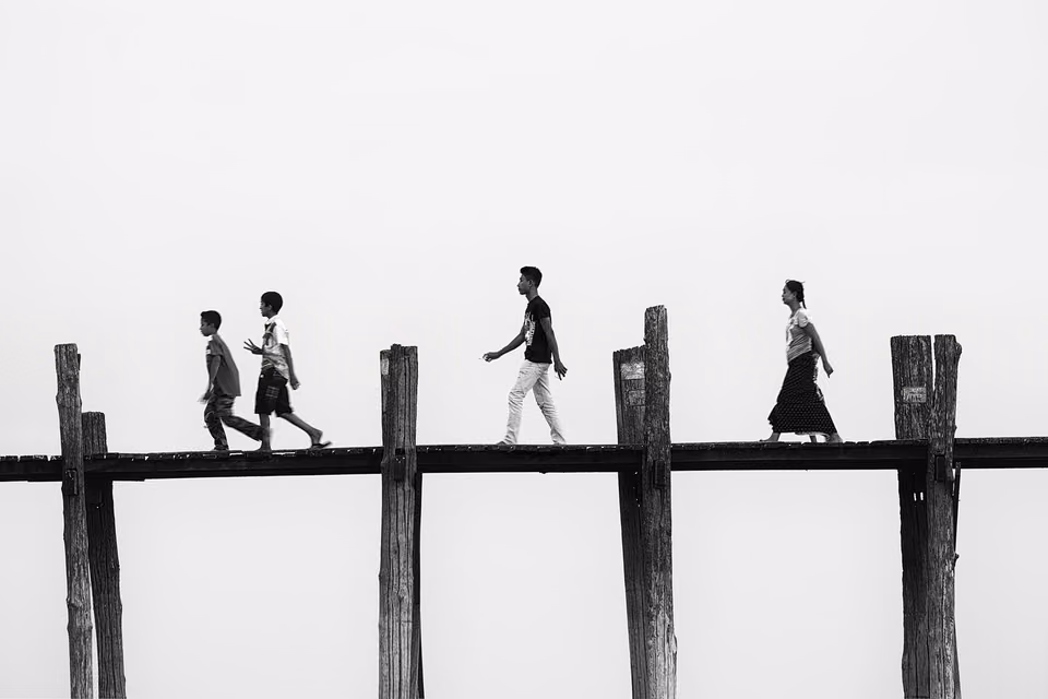 a group of people walking across a wooden bridge
