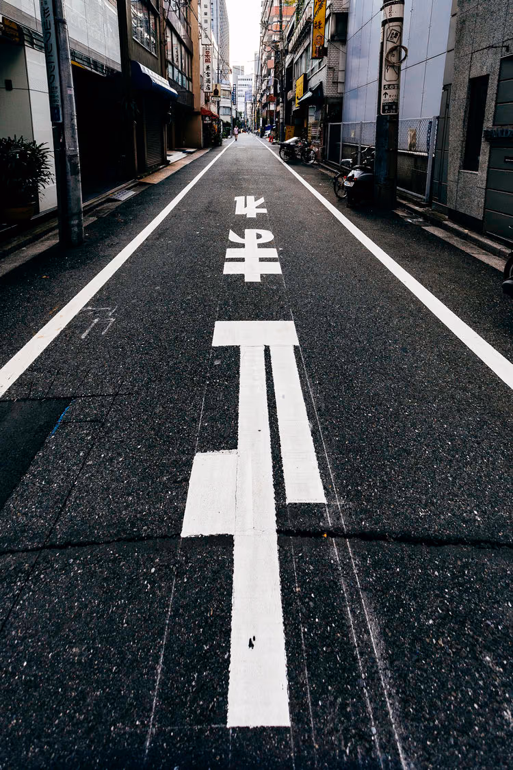 a street with a white line and a japanese writing
