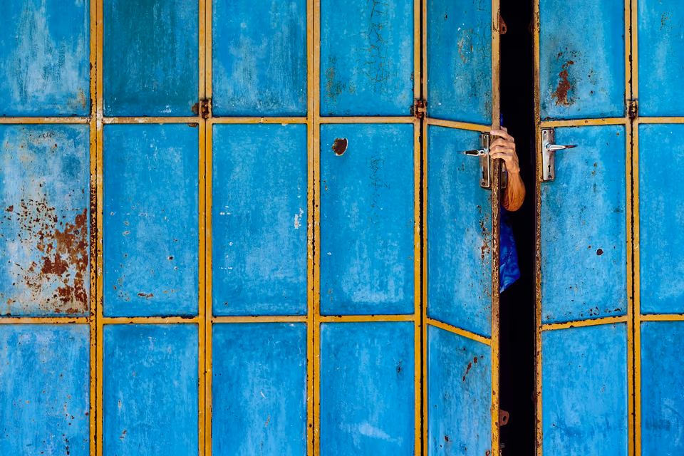 a person peeking through a blue door
