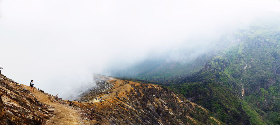 a person standing on a mountain top with a foggy sky
