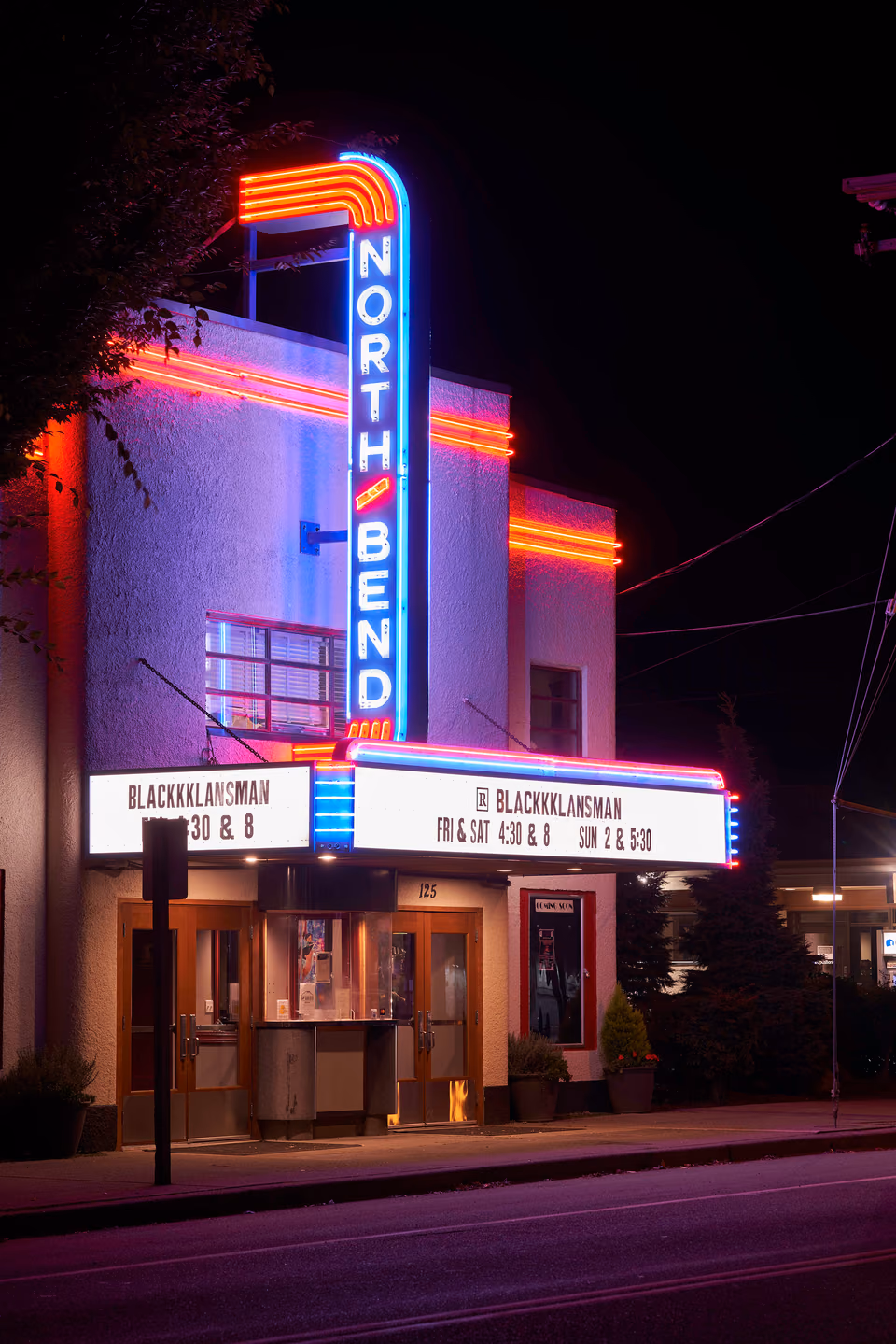 a theater with a neon sign on the side of the building
