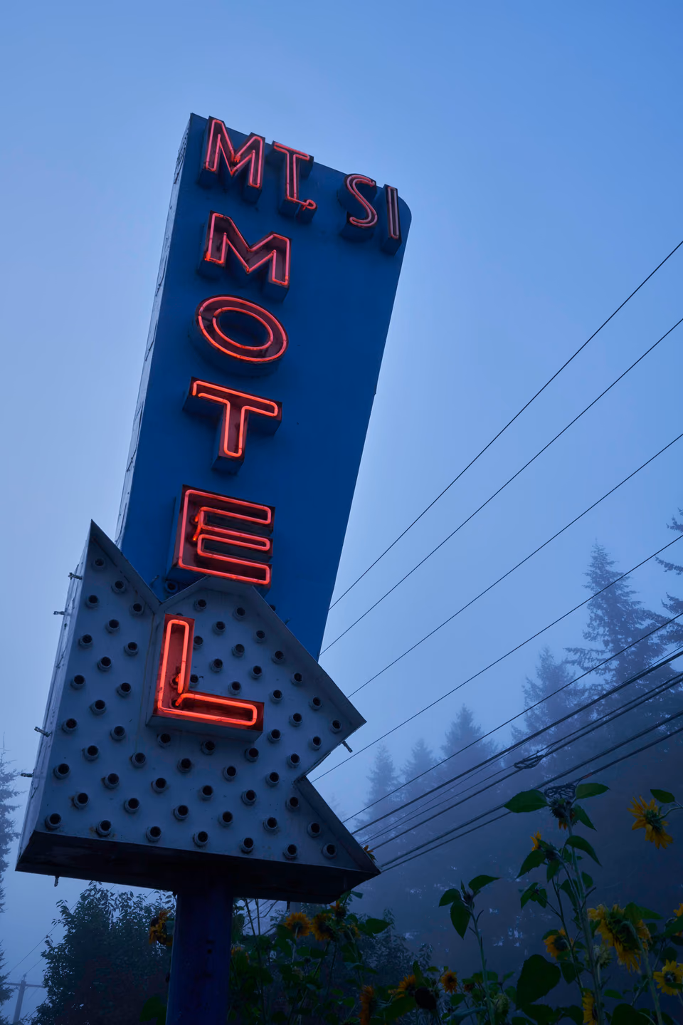 a neon motel sign in the foggy night sky
