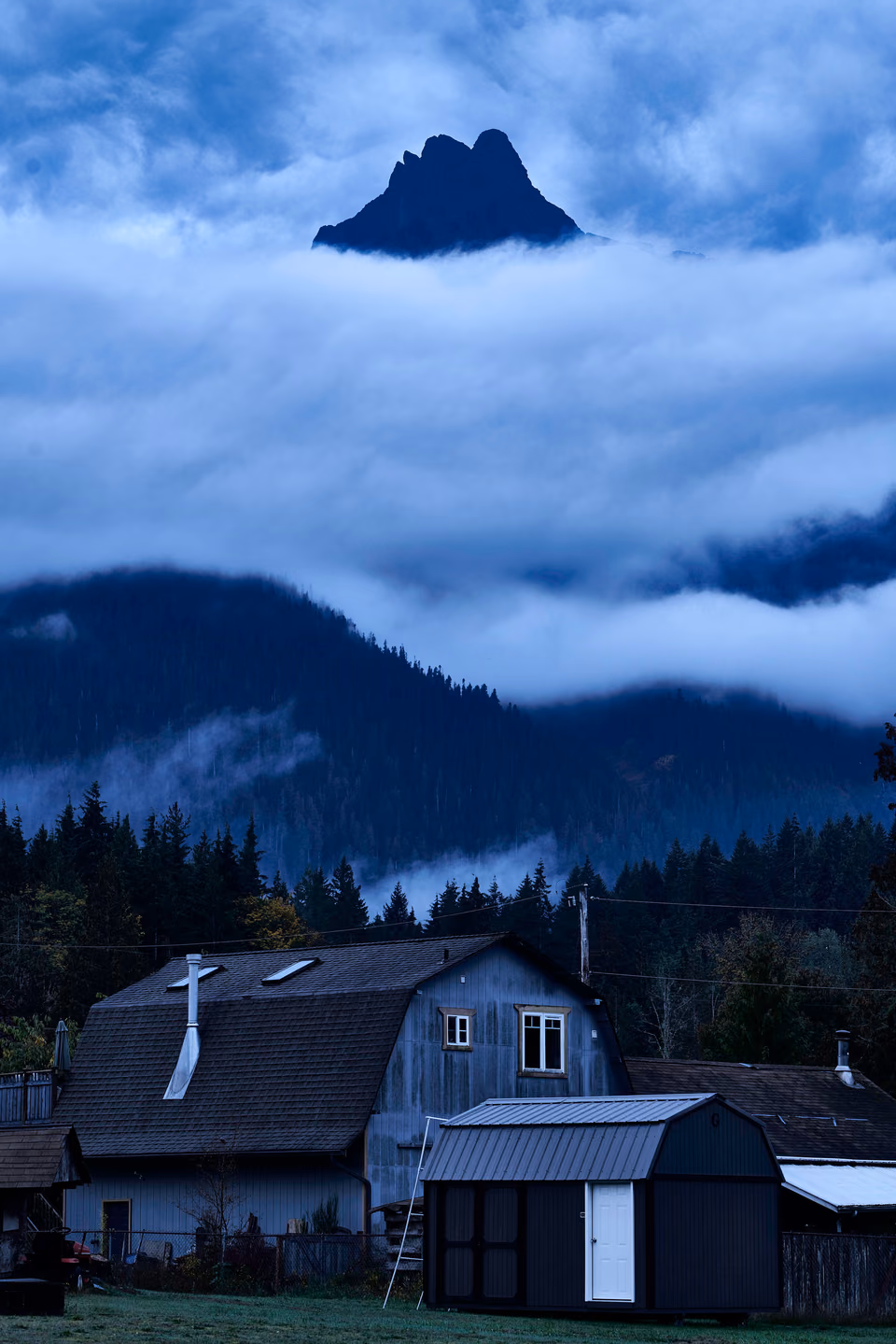 a barn with a mountain in the background
