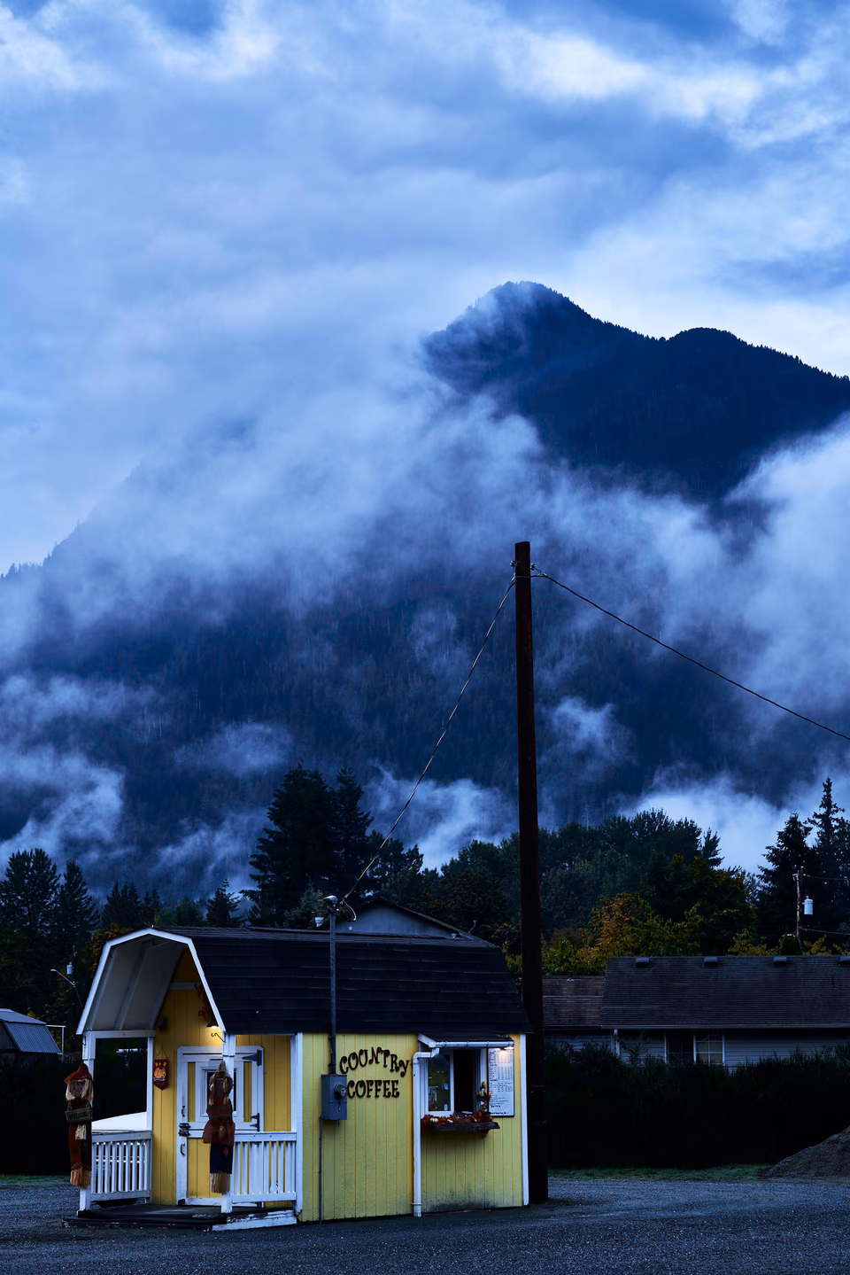 a yellow building with a yellow roof and a mountain in the background
