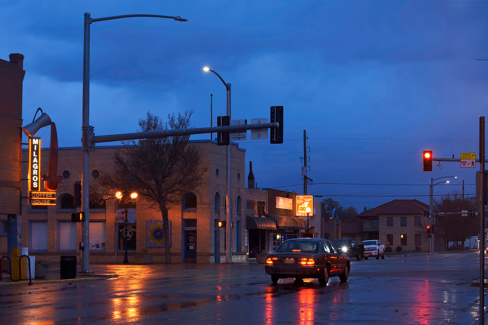 a wet street with a car driving down it
