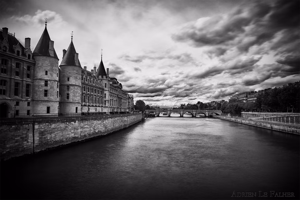 a black and white photo of a river and castle
